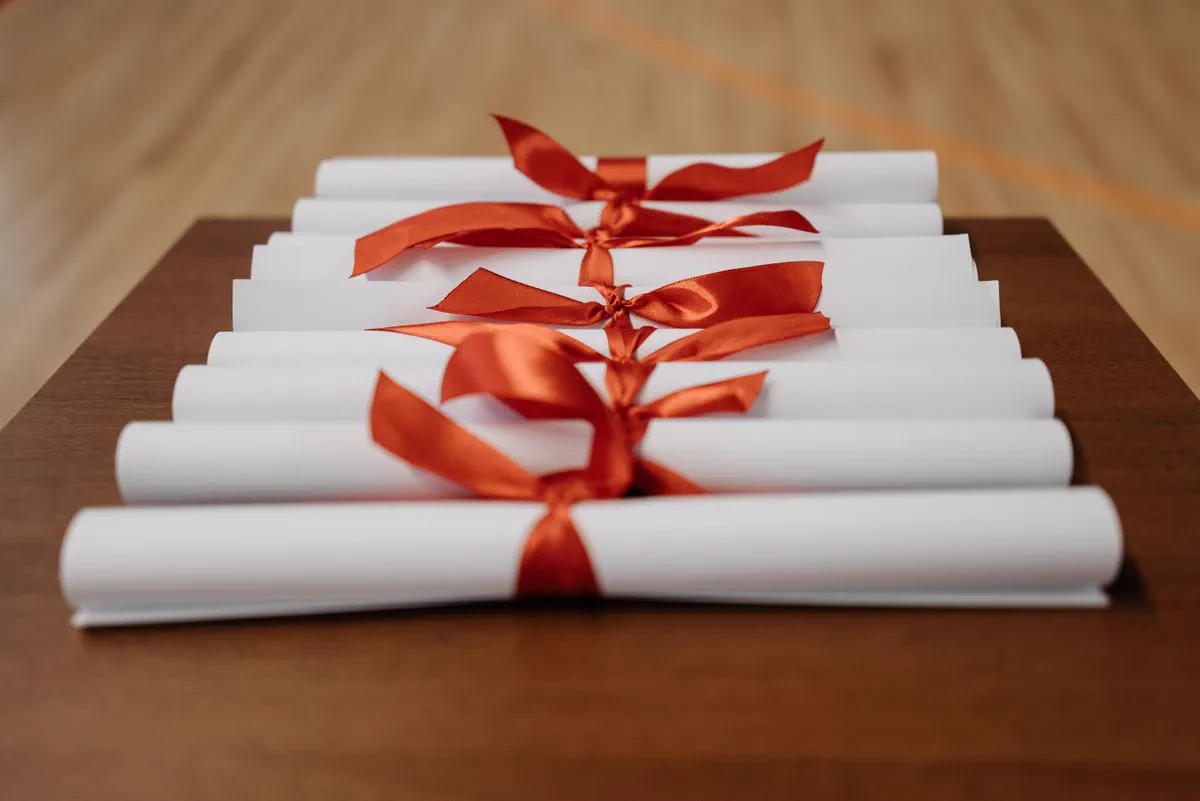 Rolled-up diplomas with red ribbons on a wooden table